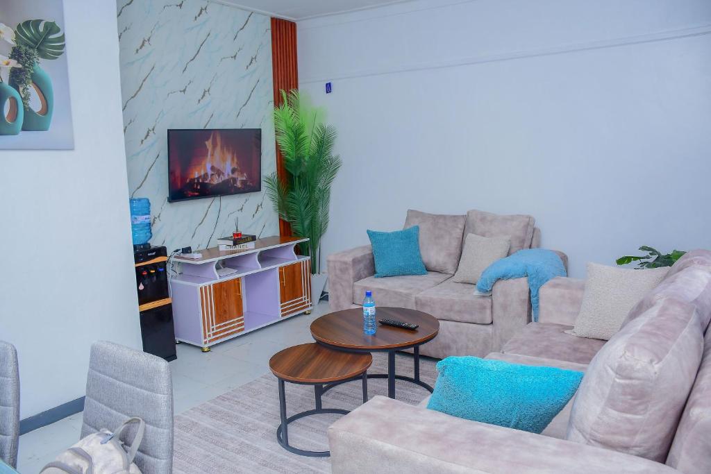 a living room with couches and a table and a tv at Meg Cozy Homes Executive 1Bedroom and 2Bedroom Apartments Near Rupa Mall The Noble Hotel & Poa Place Resort in Eldoret