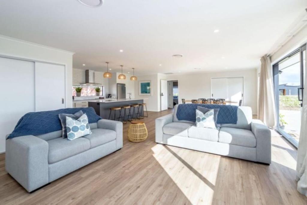 a living room with two couches and a kitchen at Arthurs Vineyard - Sleeps 10 in Martinborough