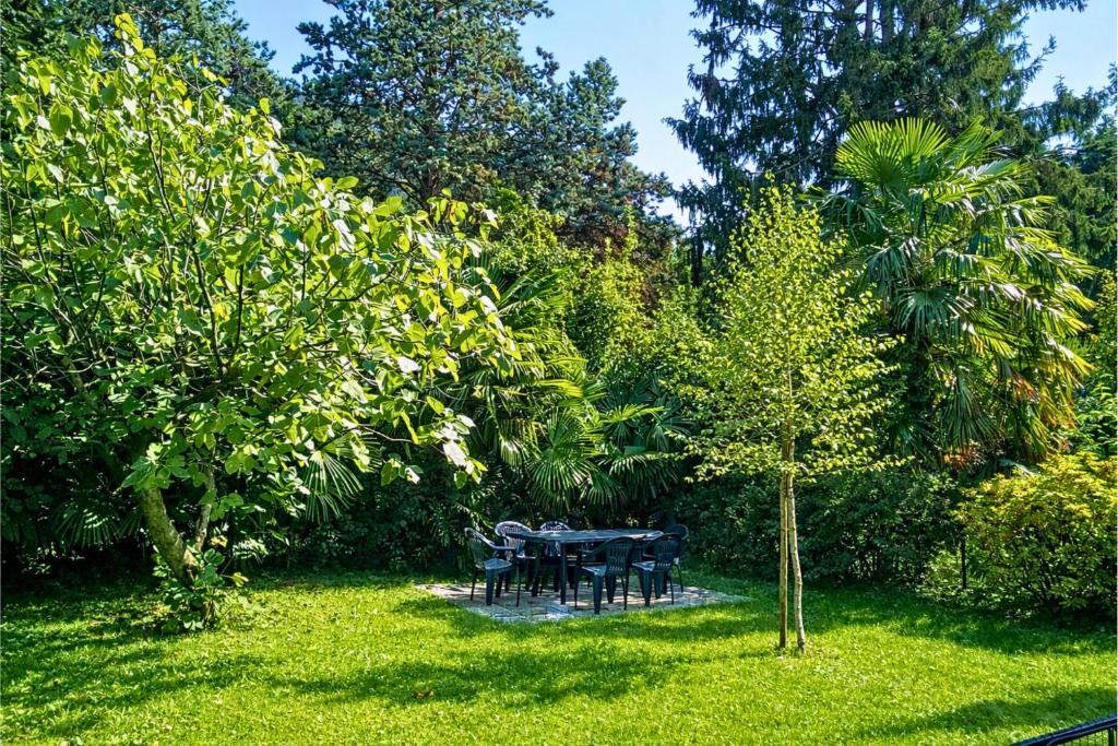 a table and chairs in a yard with trees at Casa Mariarosa in Maccagno Inferiore