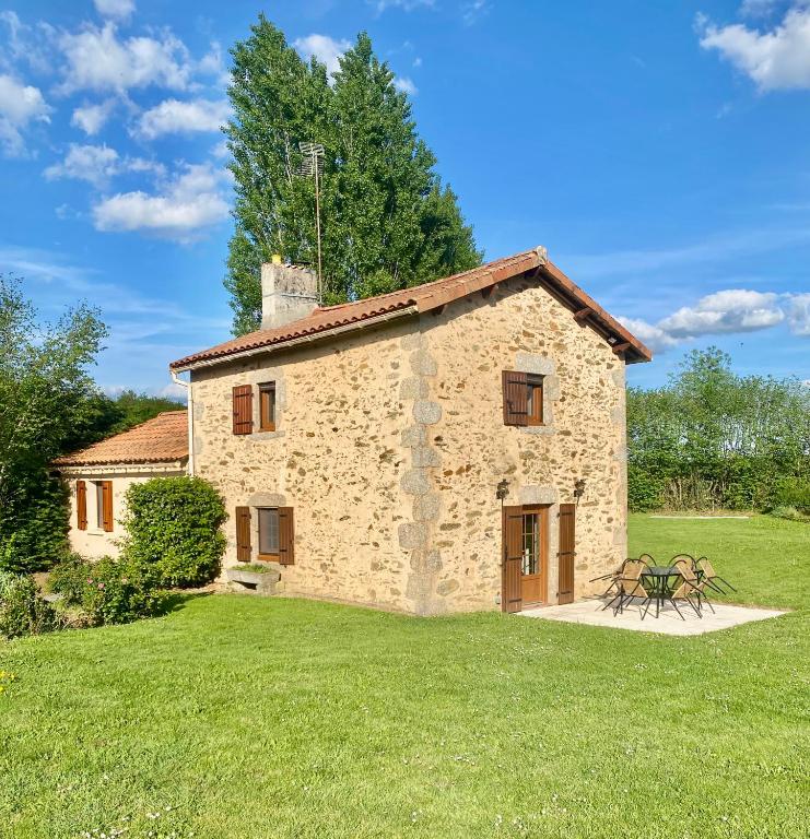 a large stone building with a grassy yard at Gîte à la campagne in Secondigny