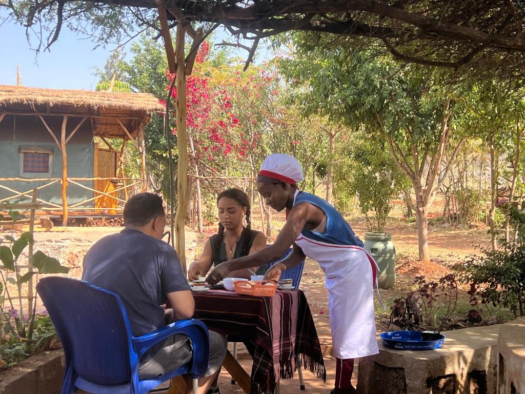 two men and a woman sitting at a table at Arbaminch eco campsite and lodge in Ārba Minchʼ