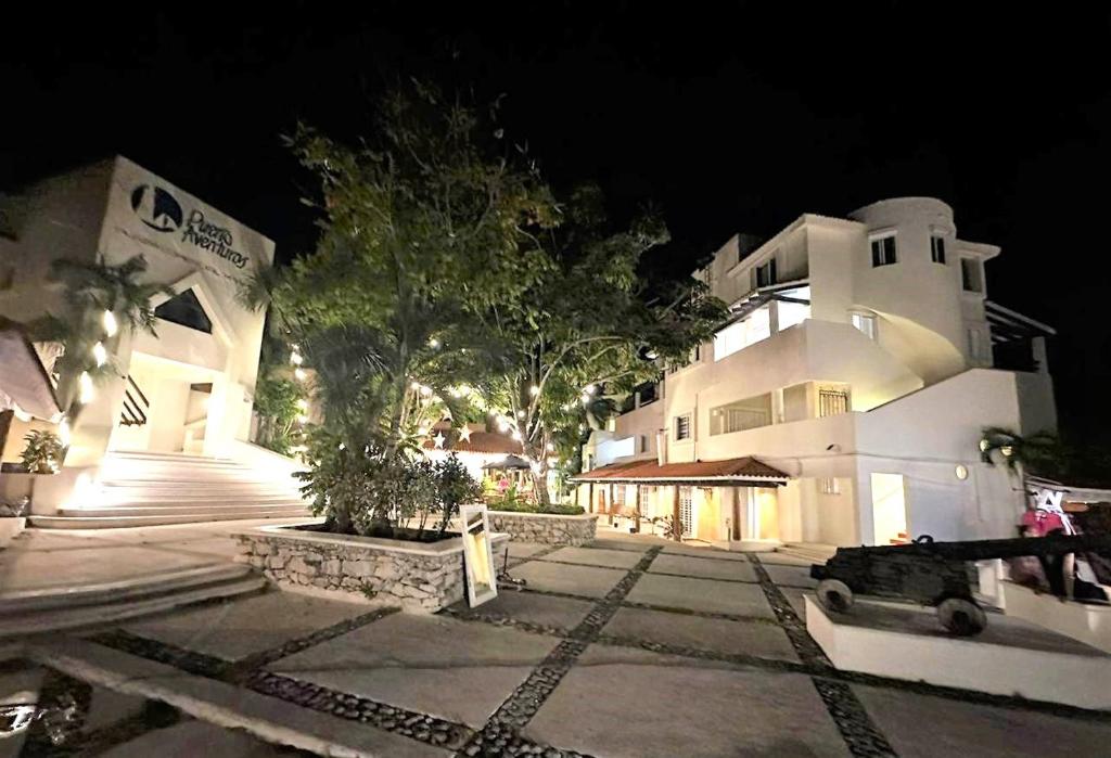 a large white building at night with trees in front of it at Beautiful apartment, prime location, beach 2 minutes away in Puerto Aventuras