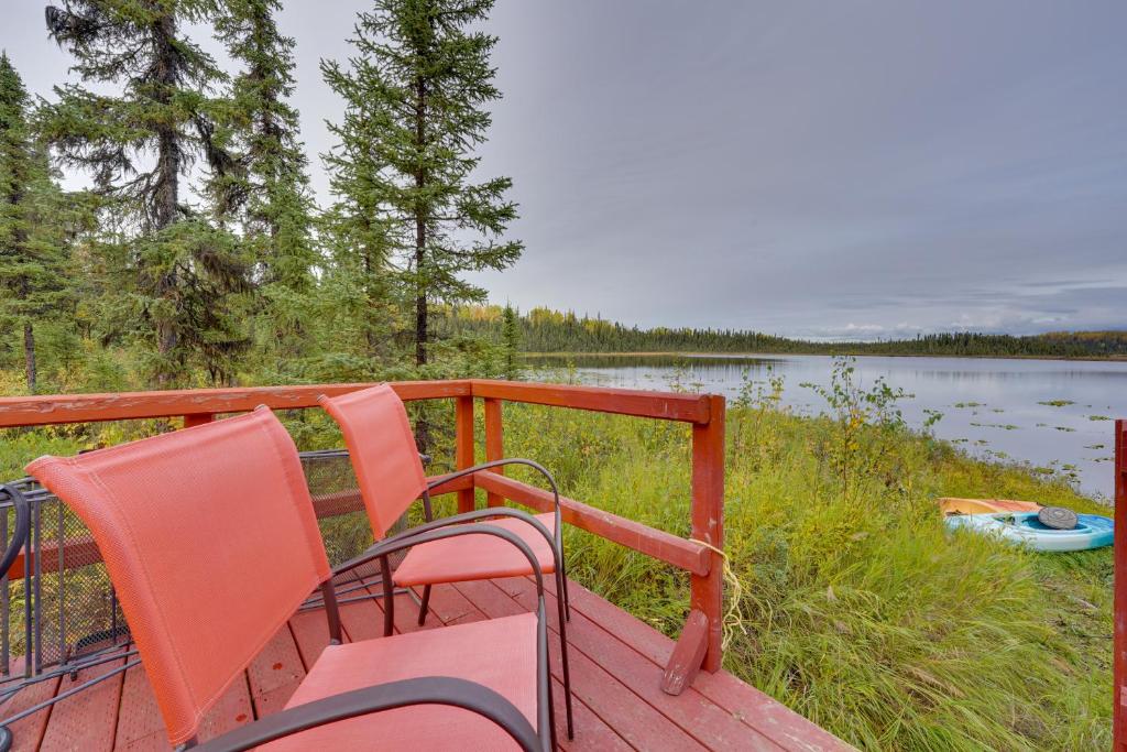 two orange chairs sitting on a deck next to a lake at 3-Cabin Base w/ Lake Access: Dogs Welcome! in Soldotna
