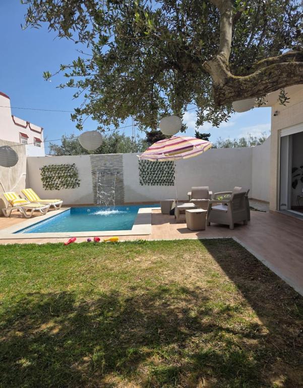 a patio with an umbrella and a swimming pool at Villa Maya House - Cap Zbib in Banī ‘Aţāʼ