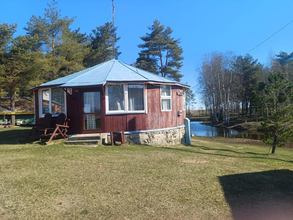a red tiny house on the side of a lake at Vasaras mājiņa pie Rāznas ezera Nr 3 in Kaunata