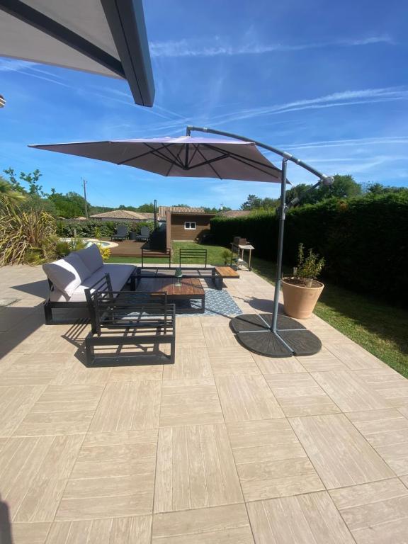 a patio with a table and an umbrella at CHAMBRE D HÔTE CHEZ Nath in Sadirac