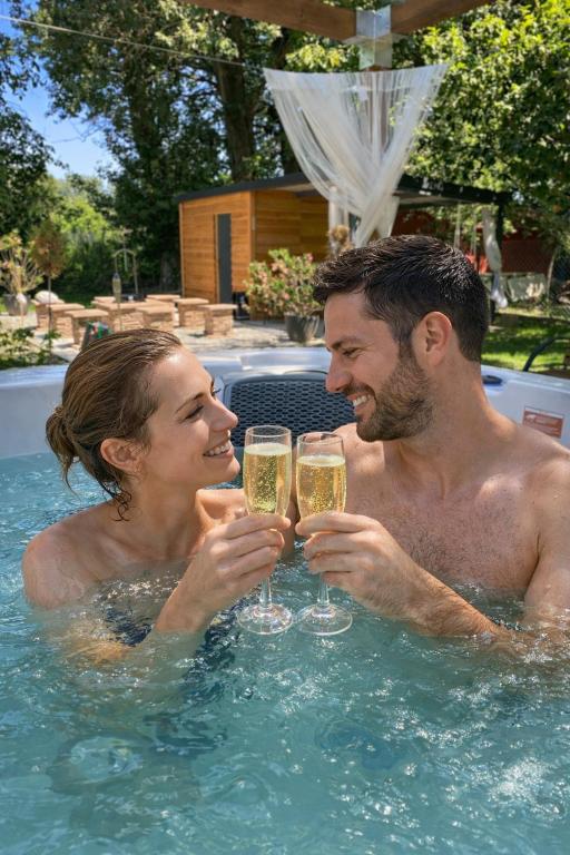 a man and woman drinking champagne in a swimming pool at Richland Ráckeve in Ráckeve