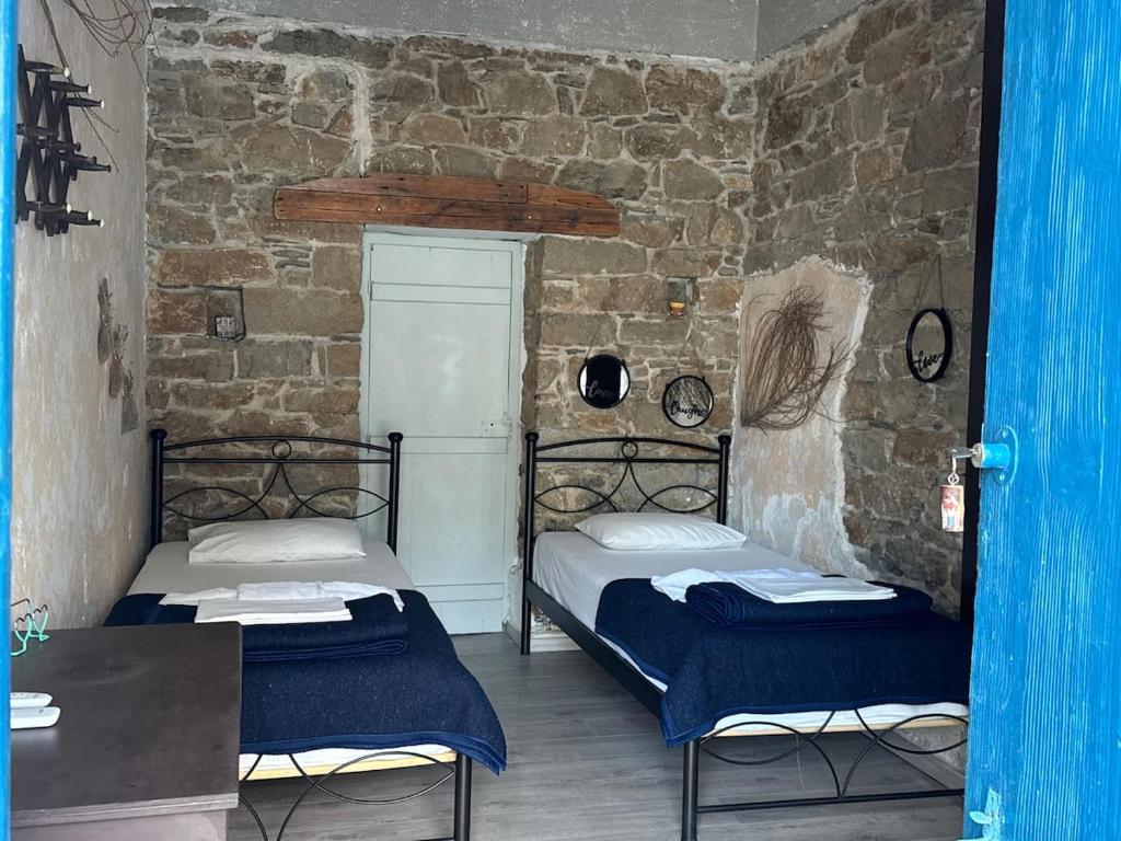 two beds in a room with a brick wall at Anthemis home II in Agios Kirykos