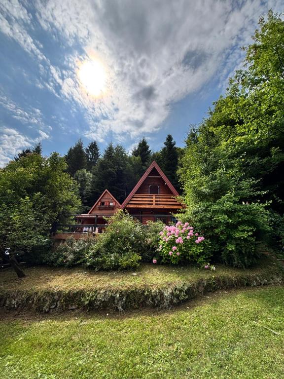 a log cabin with flowers in front of it at Twin Forest, riverside cabin in Brod na Kupi