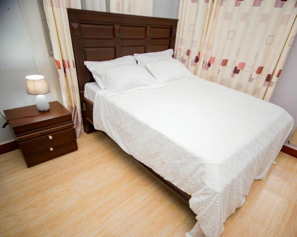 a bedroom with a large bed and a night stand with a lamp at JIV Luxury Homes in Mwanza