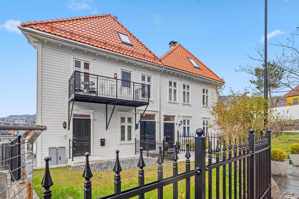 a white house with an orange roof and a black fence at Contemporary city-apartement with views of the dock! in Bergen