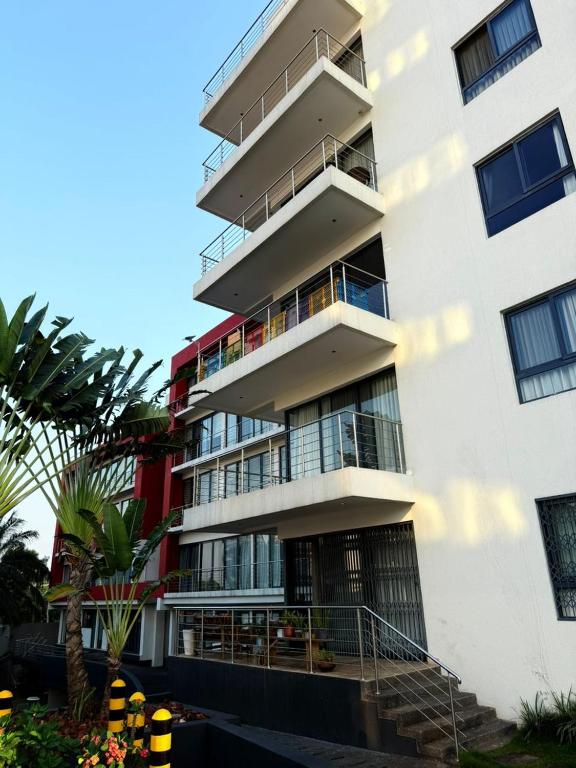 a tall white building with balconies and palm trees at Premier Place, Sky Suites in Accra