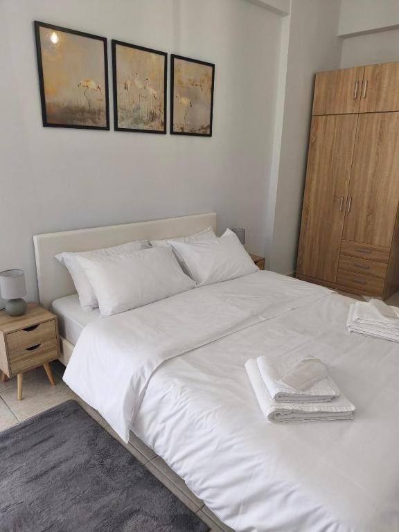 a bedroom with a white bed with a wooden cabinet at Lounetta Apartments 2 in Missolonghi