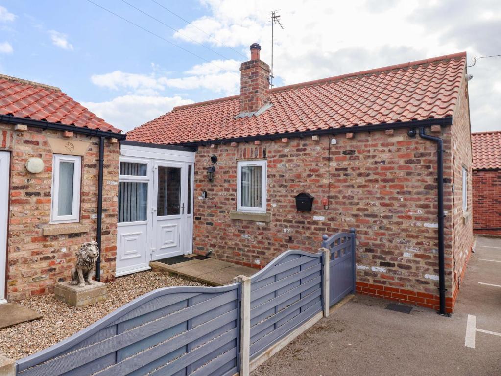 a brick house with a blue fence in front of it at Southview Bungalow in Barmston