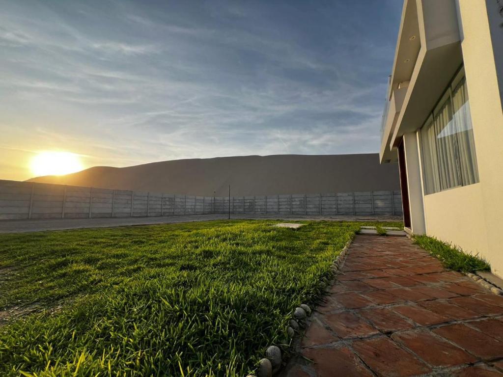 a house with a grassy yard next to a building at Residencia Privé in Ica
