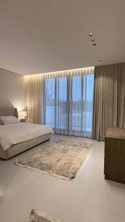 a bedroom with a large bed and large windows at فلل وشاليهات لفونيا in Buraydah