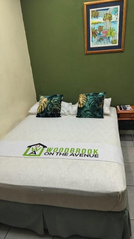 a bed in a room with a sign on it at Woodbrook on the Avenue in Port-of-Spain