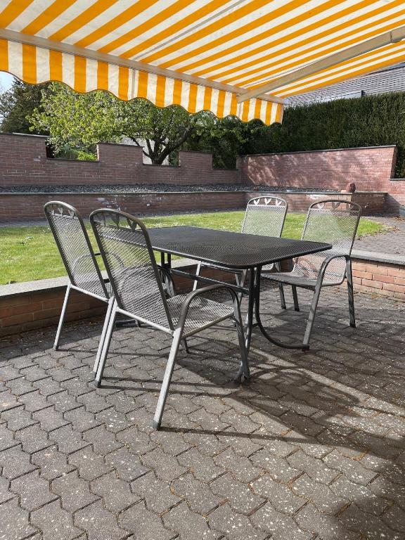 a picnic table and two chairs under an umbrella at Lieblingsplatz im Grünen - 1 Schlafzimmer in Schweich