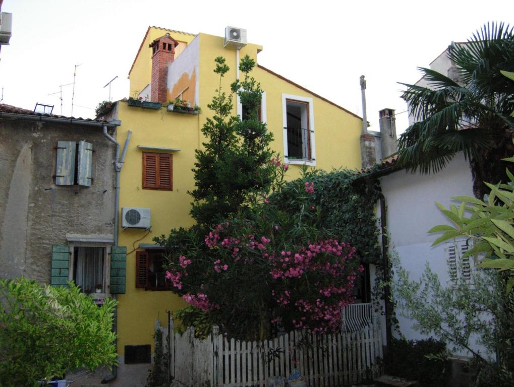 a yellow house with pink flowers on a fence at Apartments Bevk in Piran