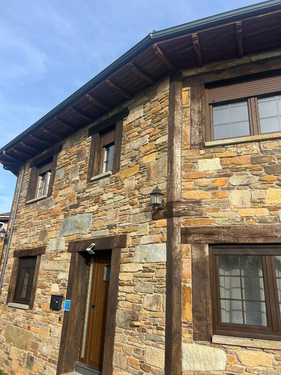 a stone building with a wooden door and windows at La Sabelona in Otero de Sanabria