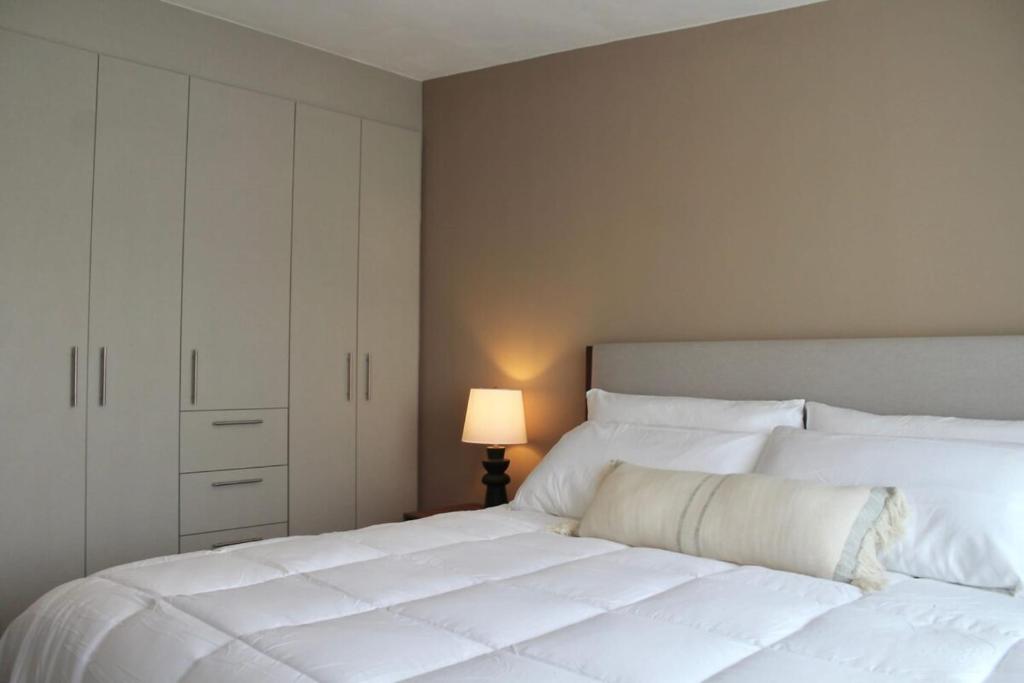 a bedroom with a large white bed and a lamp at Single Suite Unbeatable Location Internet b34 in Casa Blanca La Corregidora
