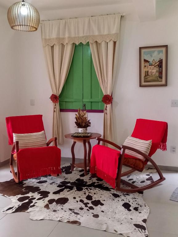 a living room with red chairs and a table at Pouso Elohim in Tiradentes