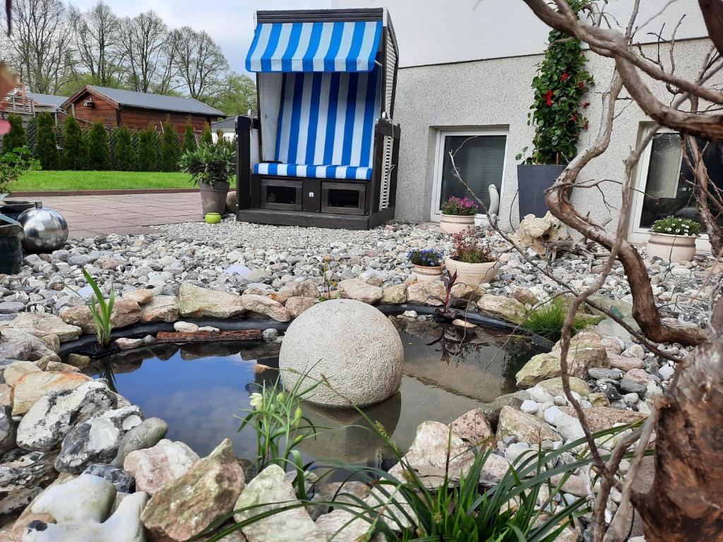 a garden with a blue and white chair and a pond at Ferienwohnung Ankerplatz Züssow in Züssow