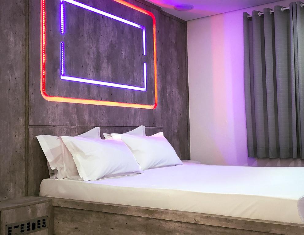 a bedroom with a bed with white pillows at Alpino Motel by Drops in Jundiaí