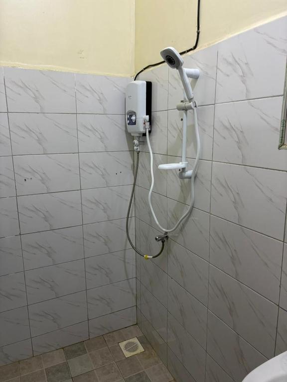 a shower in a bathroom with a hair dryer on a wall at Sahel Gardens in Kisubi