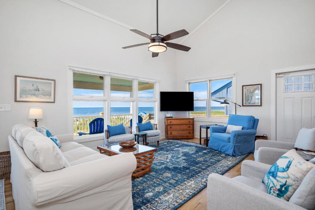 a living room with white furniture and a flat screen tv at 7th Heaven by Oak Island Accommodations in Oak Island