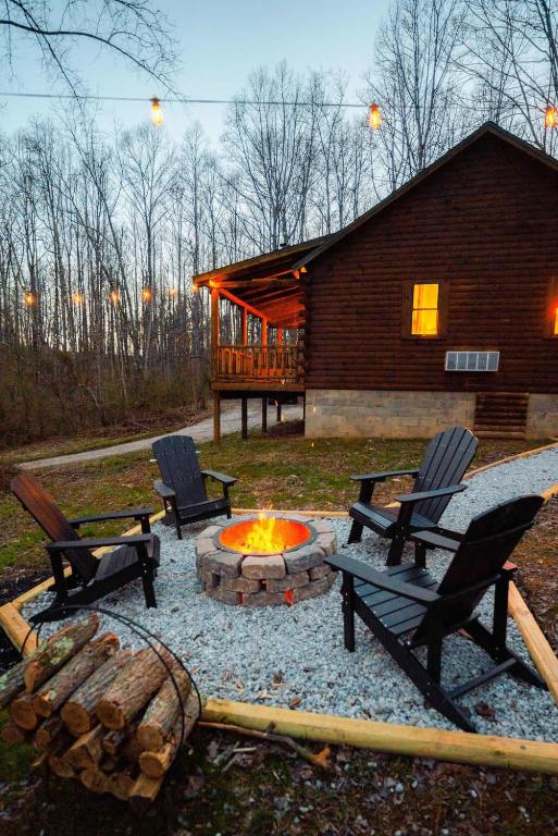 a fire pit with two chairs and a cabin at Secluded Cozy Log Cabin Villa in Creola