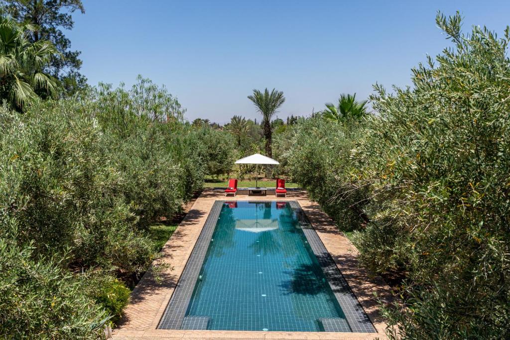 a swimming pool in the middle of a field with trees at Villa ouidane in Marrakesh