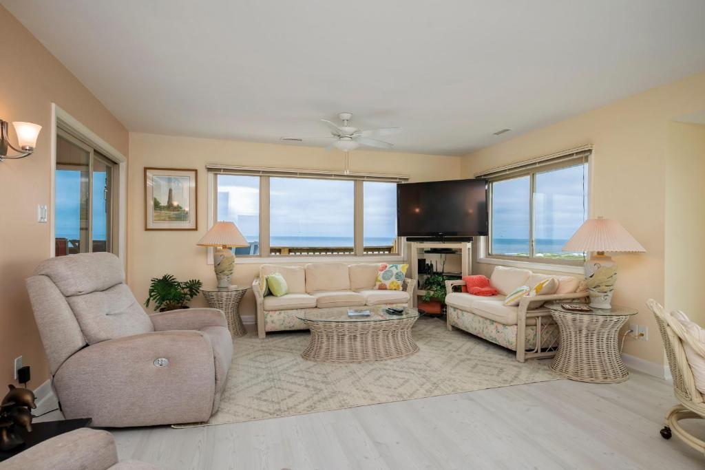 a living room with couches and chairs and windows at A Searious Sunset View by Oak Island Accommodations in Caswell Beach