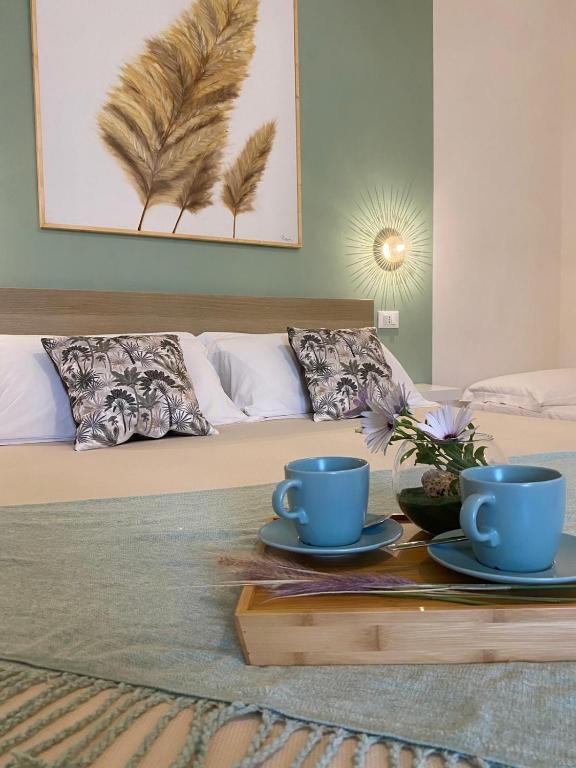 a bed with two blue cups and plates on a table at B&B La mia Isola in Castelluzzo