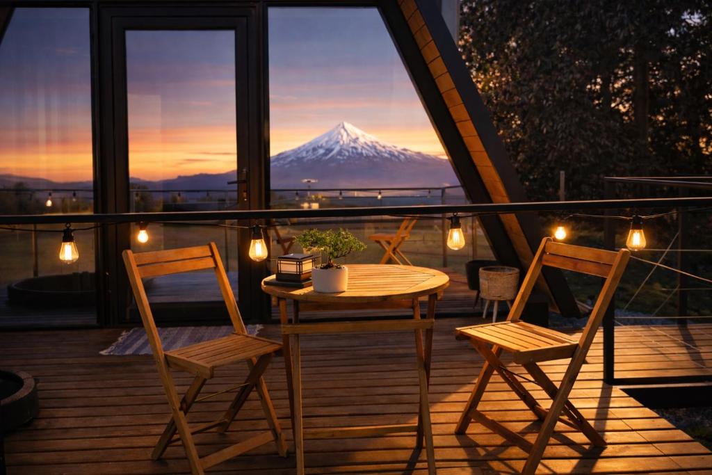 a table and chairs on a balcony with a mountain at Cabaña Con Impresionante Vista Volcan y Lago AYUN LAFQUEN in Villarrica