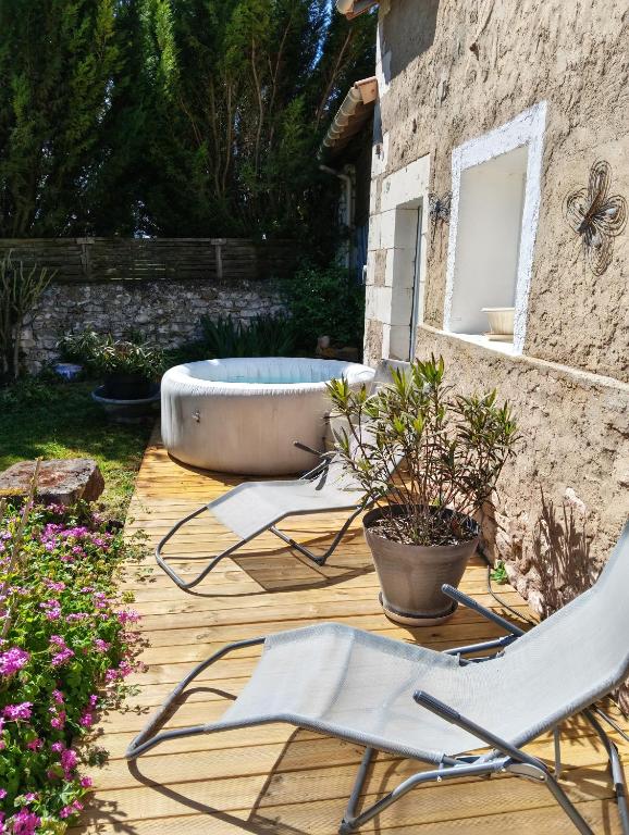 a deck with two chairs and a bath tub at La fermette de Chandigon in Antran