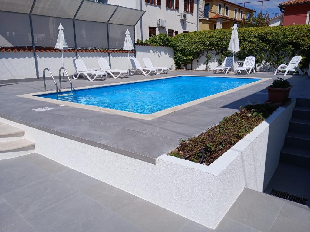 a swimming pool with chairs next to a building at House Casa Fabris with Pool in Umag