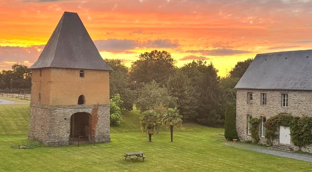 an old building in a field with a sunset in the background at Escapade au cœur du Haras in Le Mesnil-Rouxelin