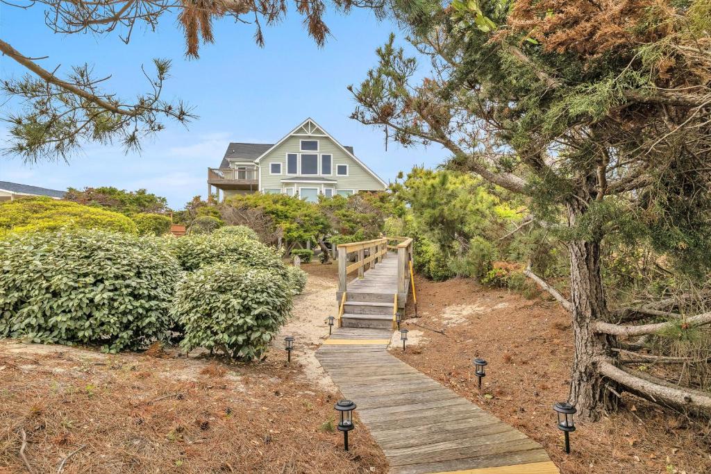 a house with a wooden staircase leading to a house at Azohva by Oak Island Accommodations in Caswell Beach