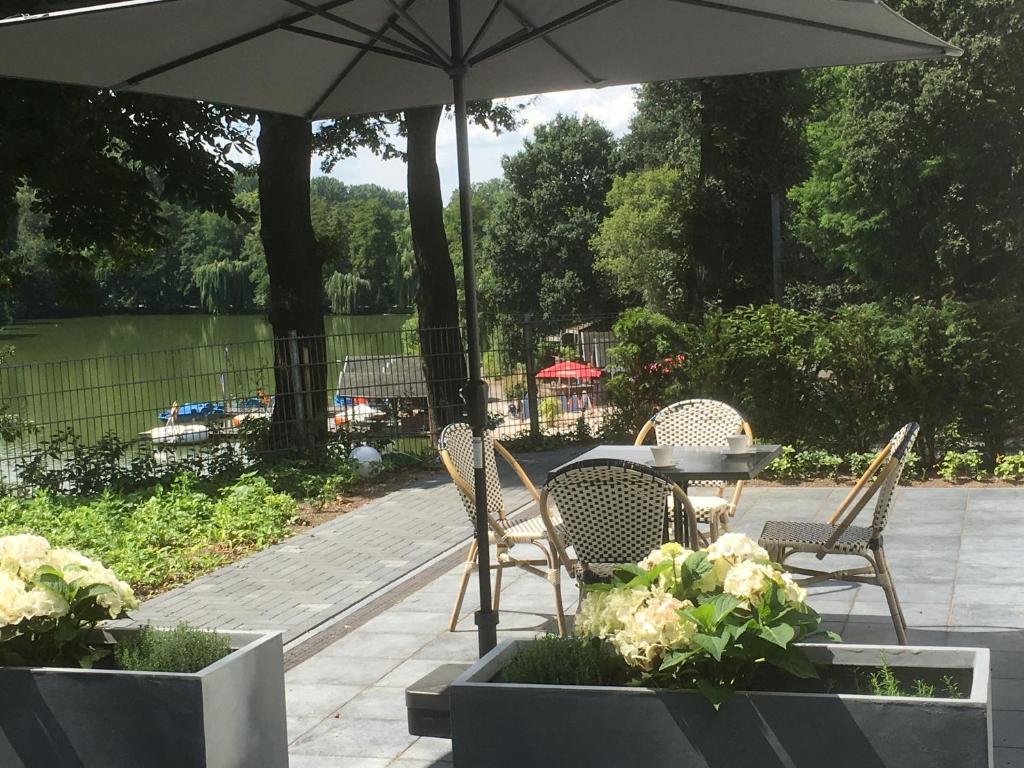 eine Terrasse mit einem Tisch, Stühlen und einem Sonnenschirm in der Unterkunft Hotel Haus Broichtal in Alsdorf