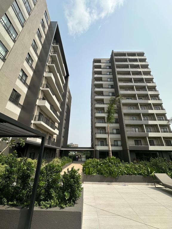two tall buildings with a palm tree in a courtyard at Delali Residence at The Bantree 5 mins from Airport in Accra