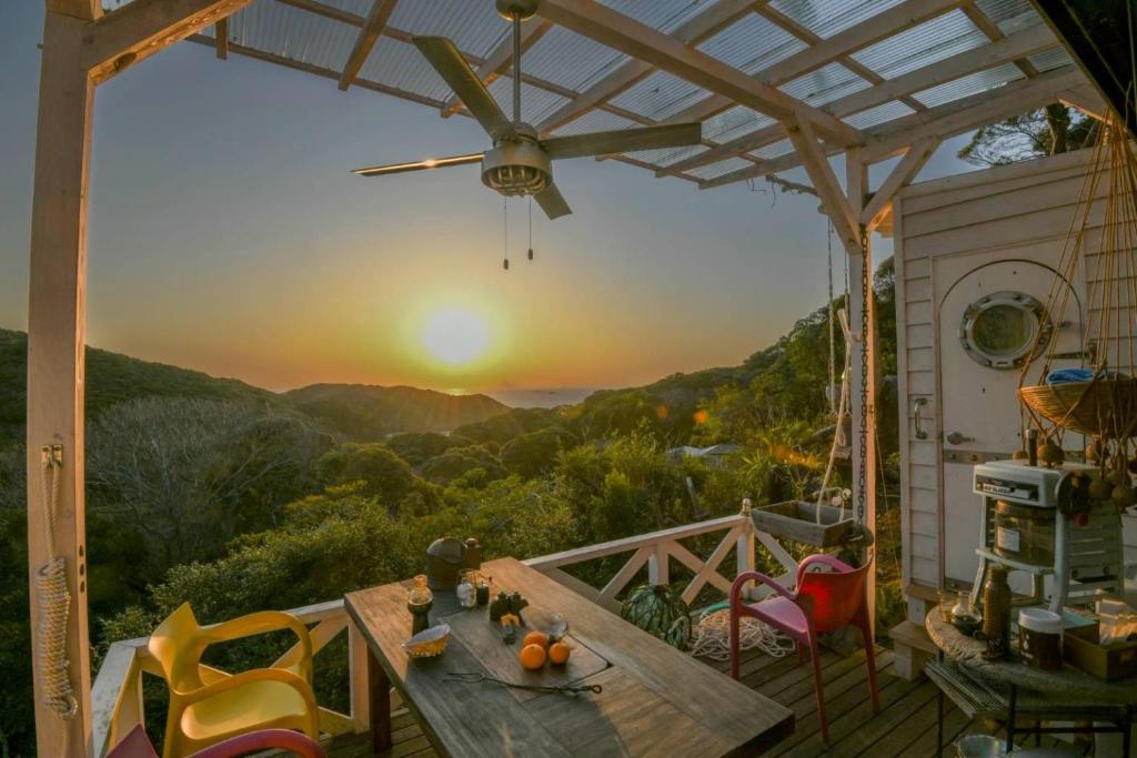 a patio with a table and chairs and a sunset at VILLE Noble Savage see view薪ストーブサウナ付き in Minamiizu