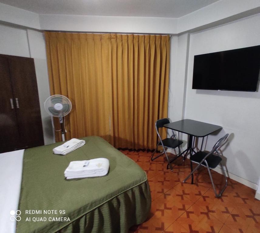 a hotel room with a bed and a table and a television at Mihostal Bless in Tacna