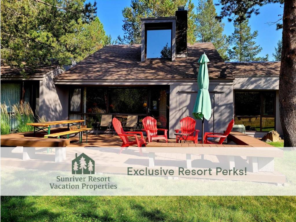 a house with red chairs and an umbrella at 89 Meadow House in Sunriver