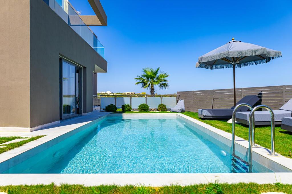 a swimming pool with an umbrella next to a house at FOGE luxury villa Agios Onoufrios in Chania