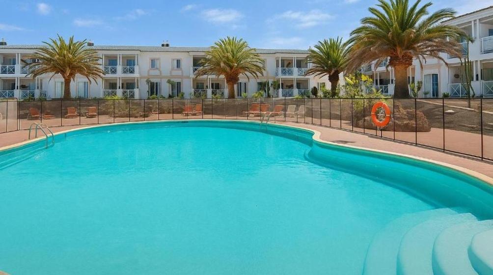a large blue swimming pool in front of a building at Apartamento Verdemare in Corralejo