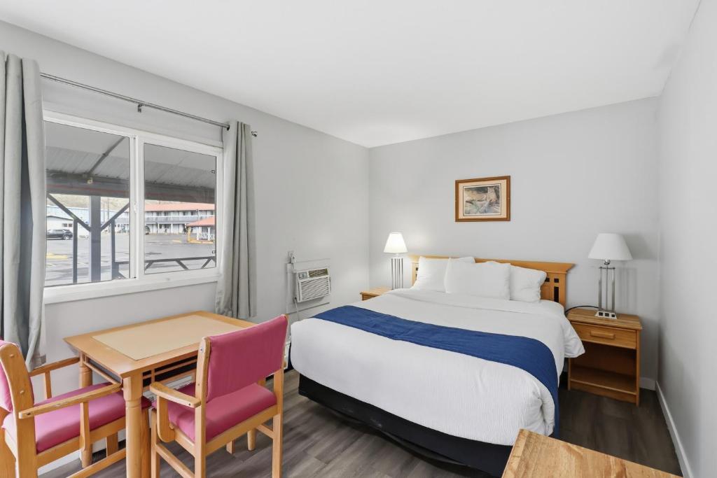 a hotel room with a bed and a table and chairs at Canada's Best Value Desert Inn & Suites in Cache Creek