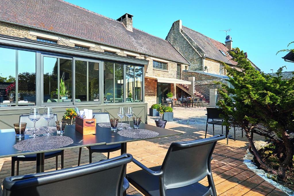 a patio with a table with wine glasses on it at Manoir'Hastings in Bénouville