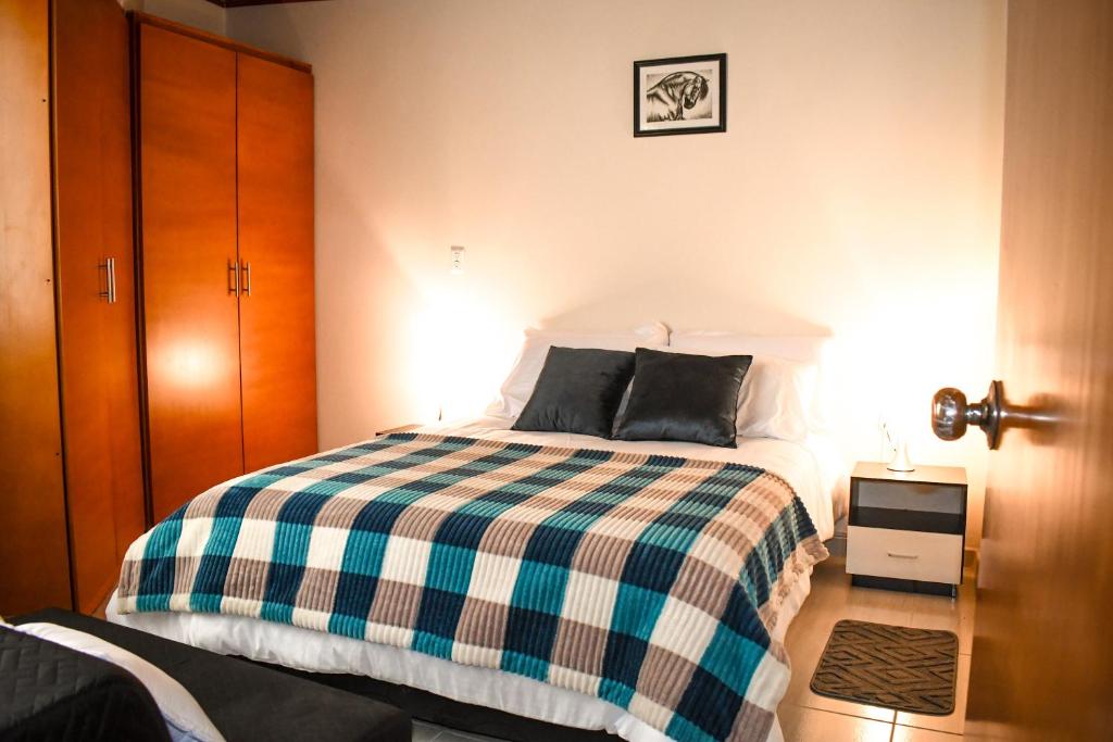 a bedroom with a bed with a checkered blanket at Apartaestudio equipado en Duitama sector UPTC in Duitama