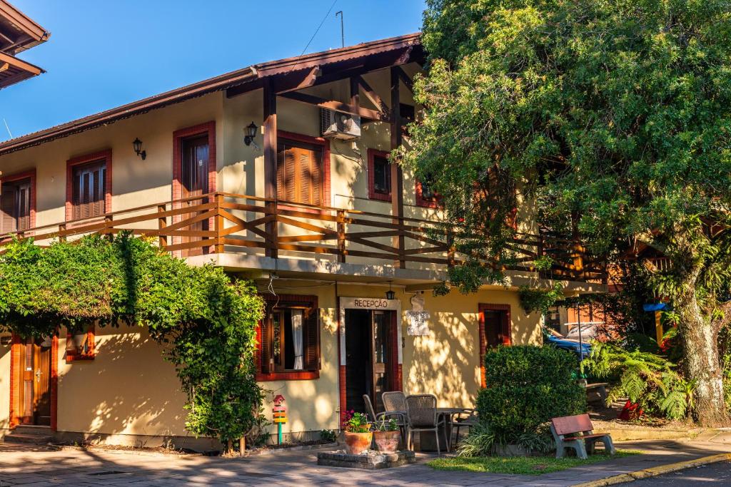 an apartment building with a balcony and a tree at Pousada Drehmer Haus in Gramado